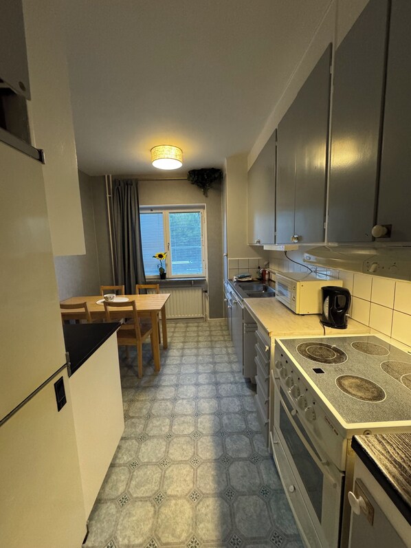 Eine kompakte Küche mit Essbereich, integriertem Backofen und einem Fenster mit Vorhängen.