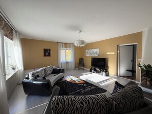 Een woonkamer met een bank, een televisie en een salontafel.