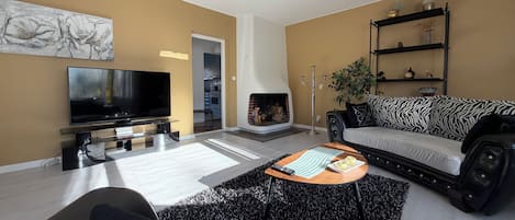 A living room with a flat-screen TV, a sofa, a coffee table, and a fireplace.