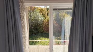 A room with a sliding glass door leading to a garden with autumn foliage.