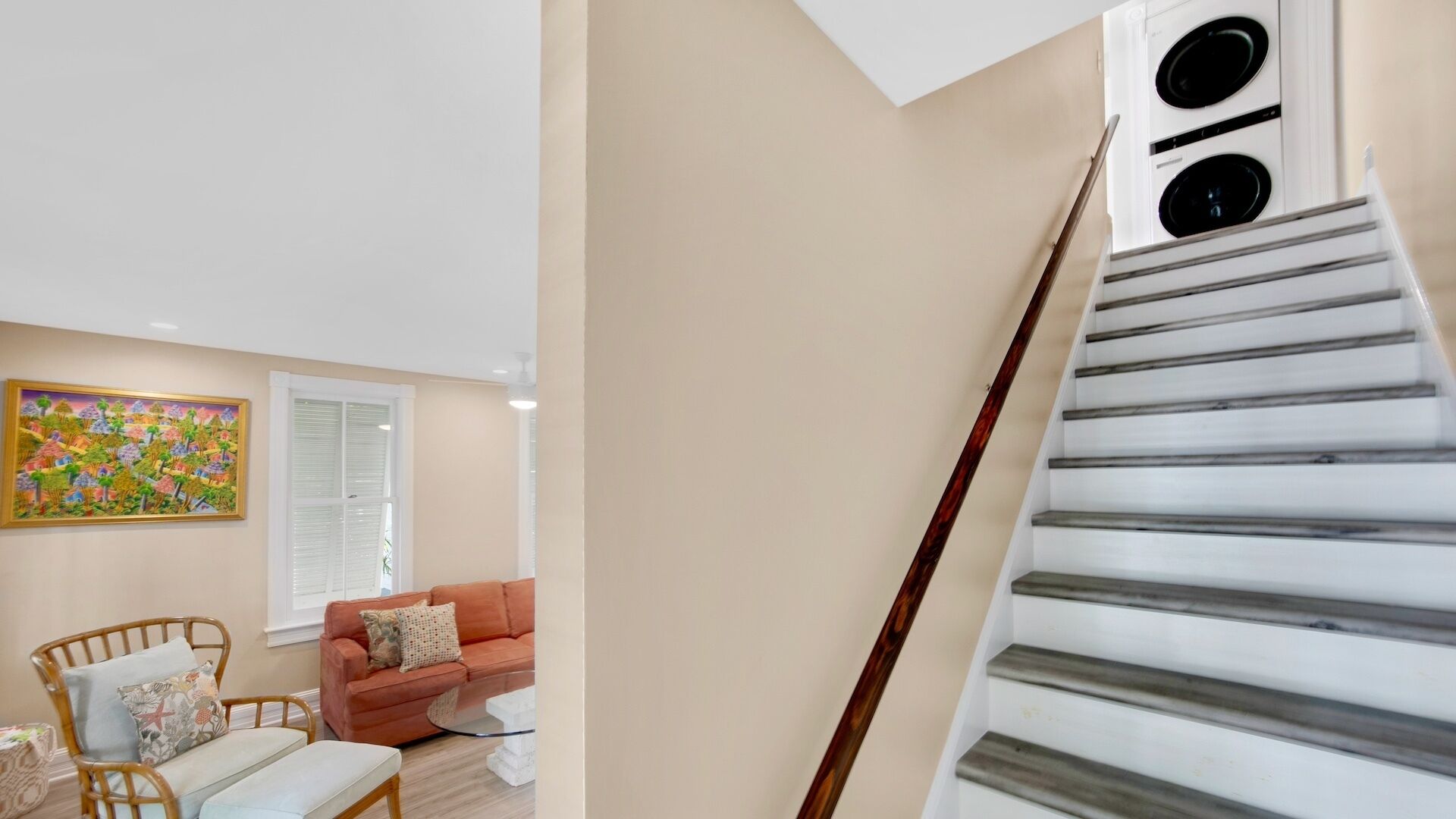 A staircase with white steps and a wooden handrail, leading to a landing.