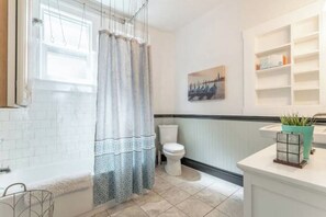 A bathroom with a shower, toilet, and a sink with a mirror. - Charming 3bed Home w/ Yard - Walk Score 91! (Portland)