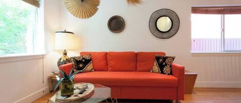 A room with a red sofa, a glass coffee table, a lamp, and wall decorations.