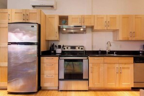 Une cuisine dotée de meubles en bois, d’un réfrigérateur en acier inoxydable, d’une cuisinière et d’un lave-vaisselle.