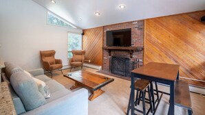 A living room with a fireplace, a sofa, two armchairs, a coffee table, and a bar stool. - Local`s Condo in Vail, Steps from Ski Shuttle (Vail)