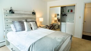 A bedroom with a bed, bedside tables, a lamp, a wardrobe, and a small kitchenette. - Local`s Condo in Vail, Steps from Ski Shuttle (Vail)