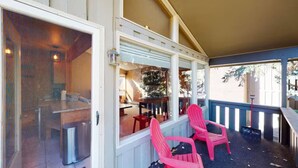 A covered porch with two red chairs, a dining table, and a view of the interior. - Local`s Condo in Vail, Steps from Ski Shuttle (Vail)