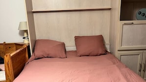 Un dormitorio con cama, cabecera de madera y mesita de noche con lámpara.
