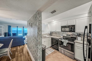 A modern kitchen with white cabinets, stainless steel appliances, and a view to the outside. - FREE Golf & Perks! Mariner West 504 Beachfront Swimming Pool, Tennis & Grill! (Panama City Beach)