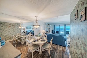 A dining area with a round table, chairs, and hanging light fixtures. - FREE Golf & Perks! Mariner West 504 Beachfront Swimming Pool, Tennis & Grill! (Panama City Beach)