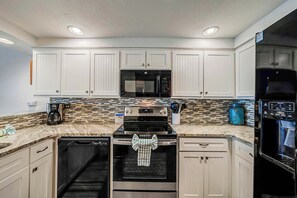 A kitchen with white cabinets, a microwave, a stove, and a dishwasher.