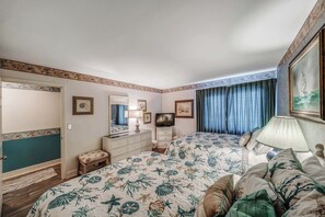 A bedroom with two beds, a dresser, a television, and a window with curtains. - FREE Golf & Perks! Mariner West 504 Beachfront Swimming Pool, Tennis & Grill! (Panama City Beach)
