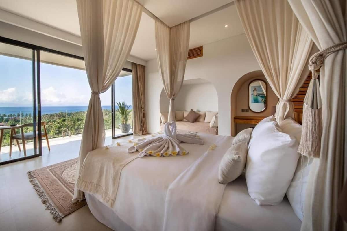 A spacious bedroom with a large bed, a view of the ocean, and a balcony.