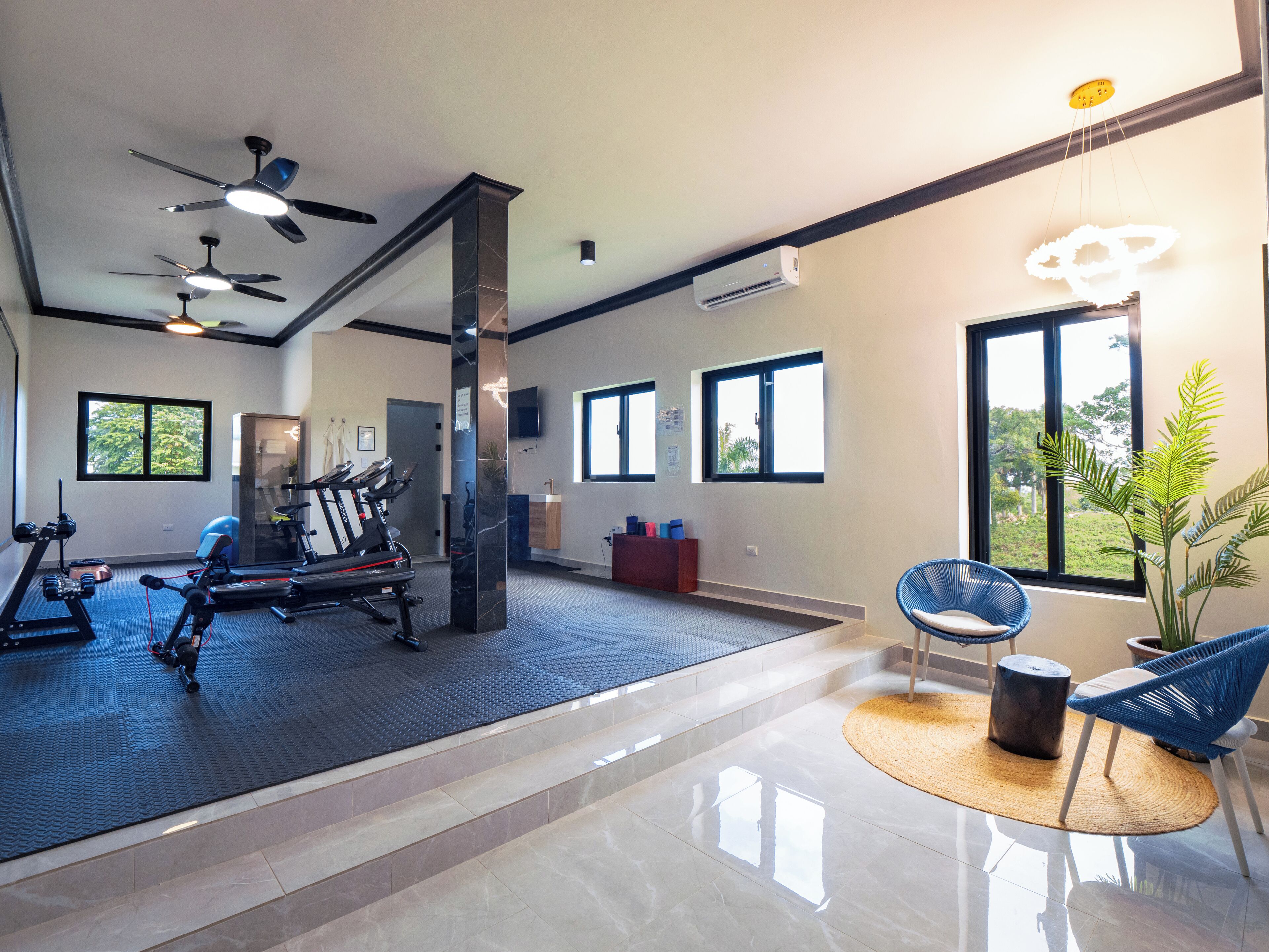 A spacious gym with exercise equipment, large windows, and a modern design.