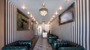 A hallway with striped walls, green leather sofas, a chandelier, and a patterned floor. - La Vie Suit Hotel (Istanbul)