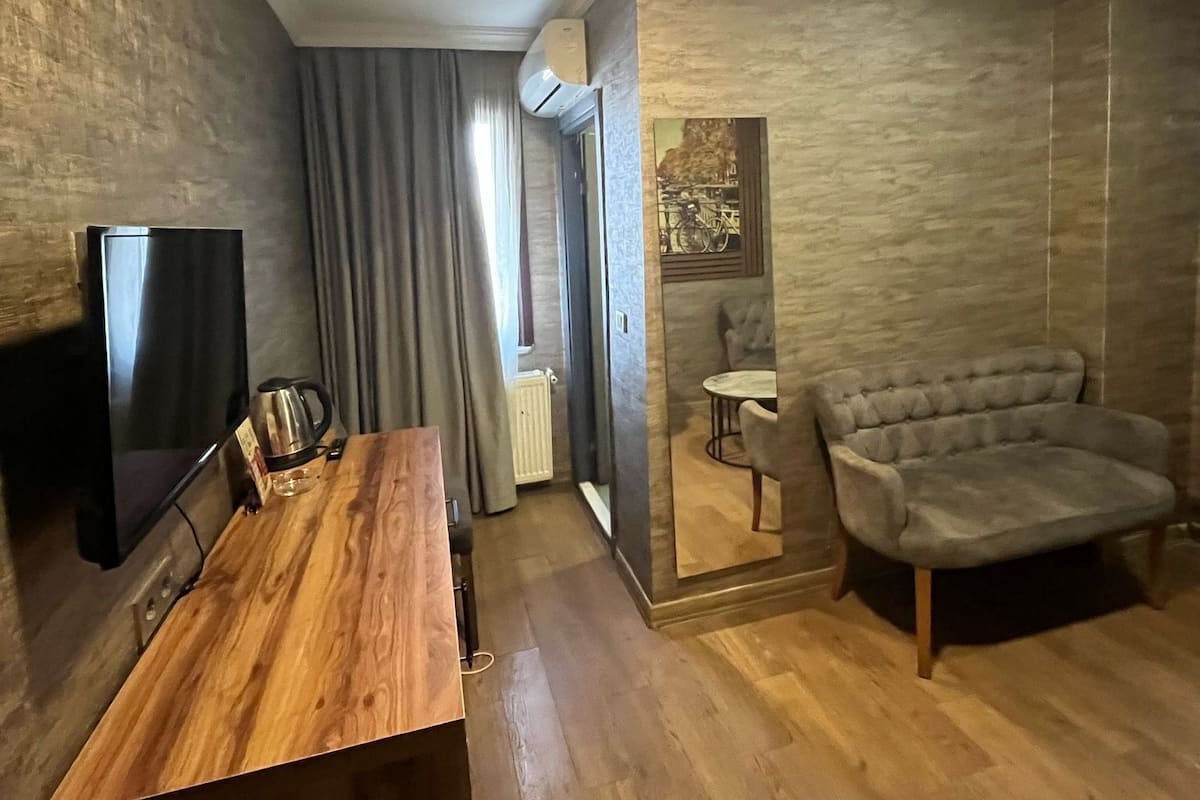 A modern living room with a wooden coffee table, a flat-screen TV, a sofa, and a dining area with a chair and table.
