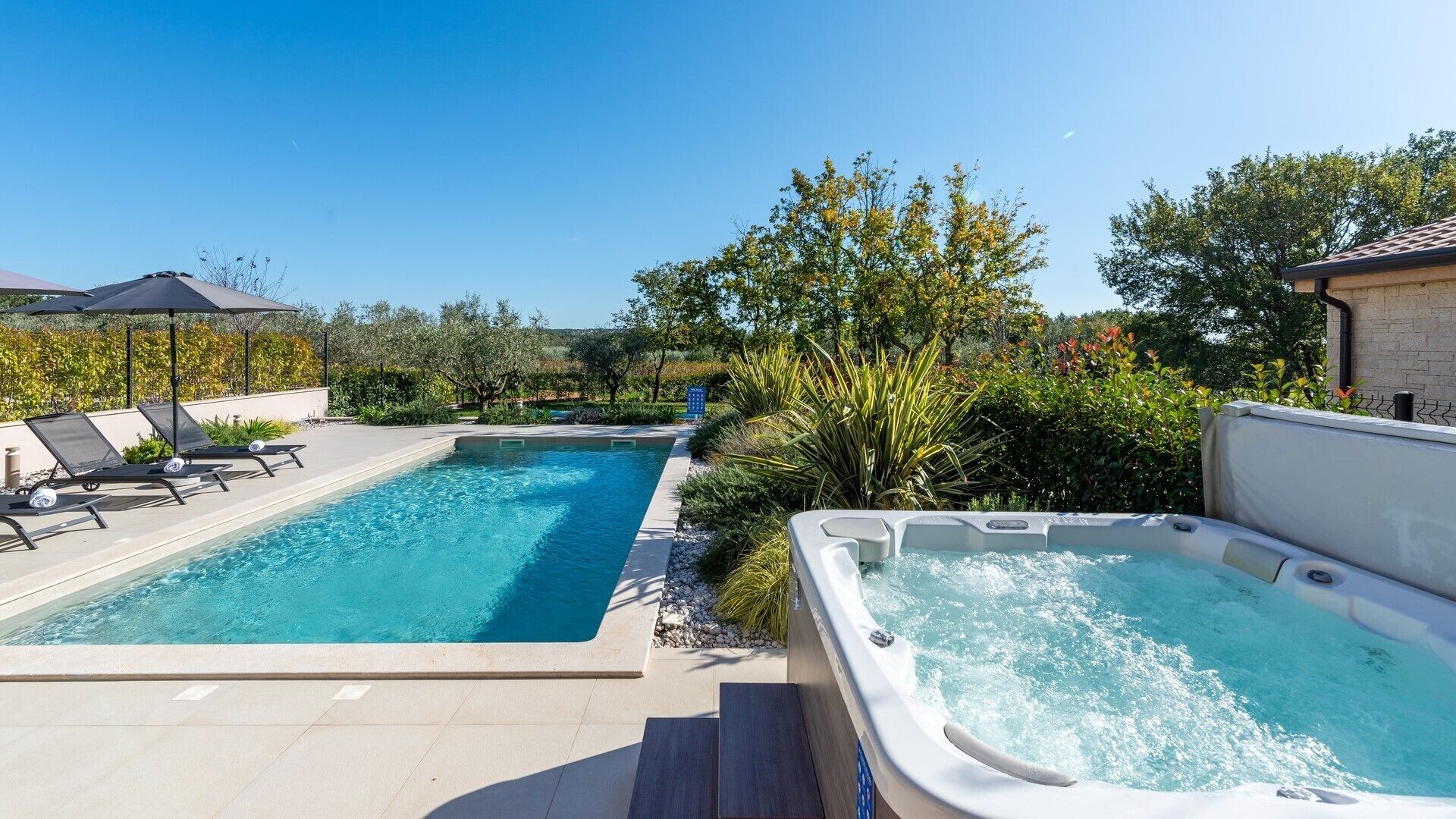 A swimming pool with lounge chairs and a hot tub.