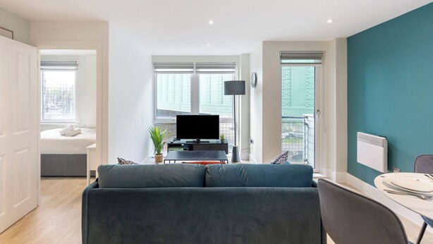 Una sala moderna con un sofá, un televisor y una zona de comedor con mesa y sillas.
