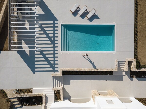 An aerial view of a swimming pool with sun loungers and a staircase.