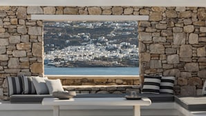 A stone-walled room with a view of a coastal town. - Villa Conza Mykonos (Mykonos)