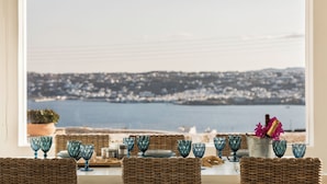 A table set with blue glassware and a bottle of champagne, overlooking a coastal view. - Villa Conza Mykonos (Mykonos)