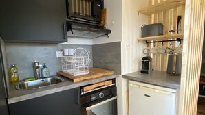 Eine kleine Küche mit Einbauofen, Mikrowelle und kleinem Kühlschrank.