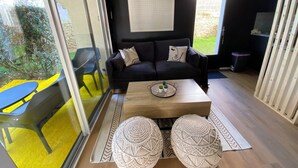 Ein modernes Wohnzimmer mit einem schwarzen Sofa, einem Couchtisch und zwei Makramee-Poufs.