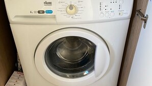 Eine Waschmaschine mit Frontlader in einem Holzschrank, mit Bedienfeld und abnehmbarer Tür.
