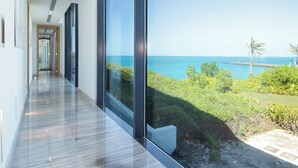 Un couloir moderne offrant une vue sur la mer et la verdure.