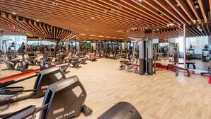 A spacious gym with various exercise equipment, a wooden ceiling, and large windows. - Capacious 3BR Apartment in Bayz Tower, Business Bay by Deluxe Holiday Homes (Dubai)
