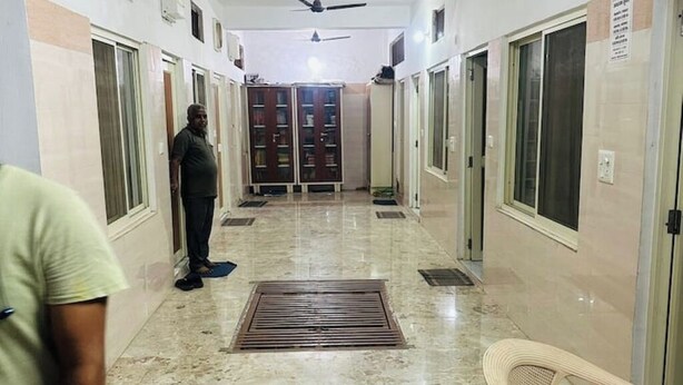 A corridor with a tiled floor, a ceiling fan, and a person standing. - Delux Room Nearby Banke Bihari Only 2min walking

 (Sunrakh Bangar)