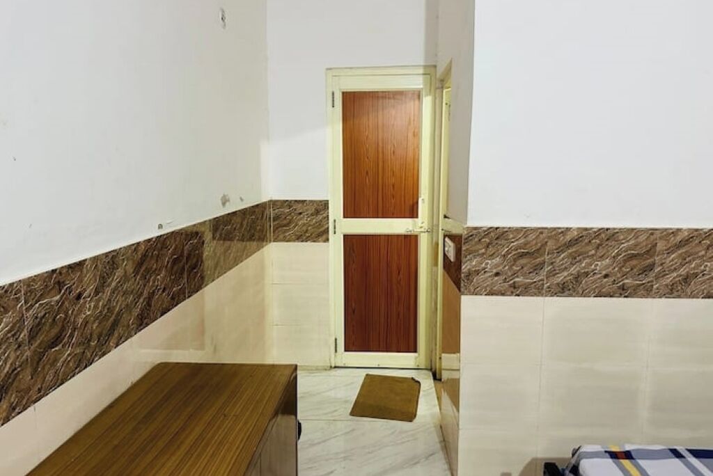 Une petite pièce avec une porte en bois, un sol carrelé de marbre et un tapis marron.