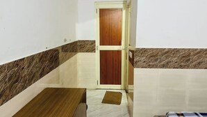 A small room with a wooden door, a marble-tiled floor, and a brown mat. - Delux Room Nearby Banke Bihari Only 2min walking

 (Sunrakh Bangar)