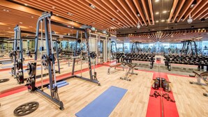 A gym with various exercise equipment, wooden flooring, and a red mat area.