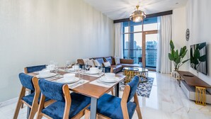 A modern living room with a dining area, large windows, and a city view.