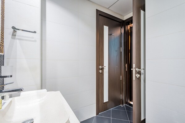 Une salle de bain moderne avec un lavabo blanc, un porte-serviettes et une porte en bois.