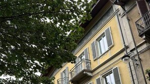 Un immeuble à plusieurs étages, doté d’une façade jaune, avec un magasin au rez-de-chaussée, et une rue pavée.