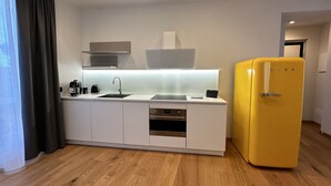 Une cuisine moderne avec un plan de travail blanc, des appareils en acier inoxydable et un réfrigérateur jaune.