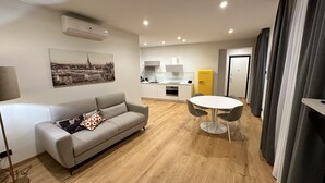 Un salon moderne comprenant un canapé, une table à manger avec des chaises, un coin cuisine et un réfrigérateur jaune.