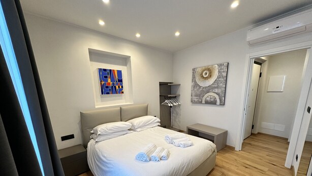 Une chambre à coucher moderne, dotée d’un grand lit, de tables de chevet, d’une armoire et d’œuvres d’art accrochées aux murs.