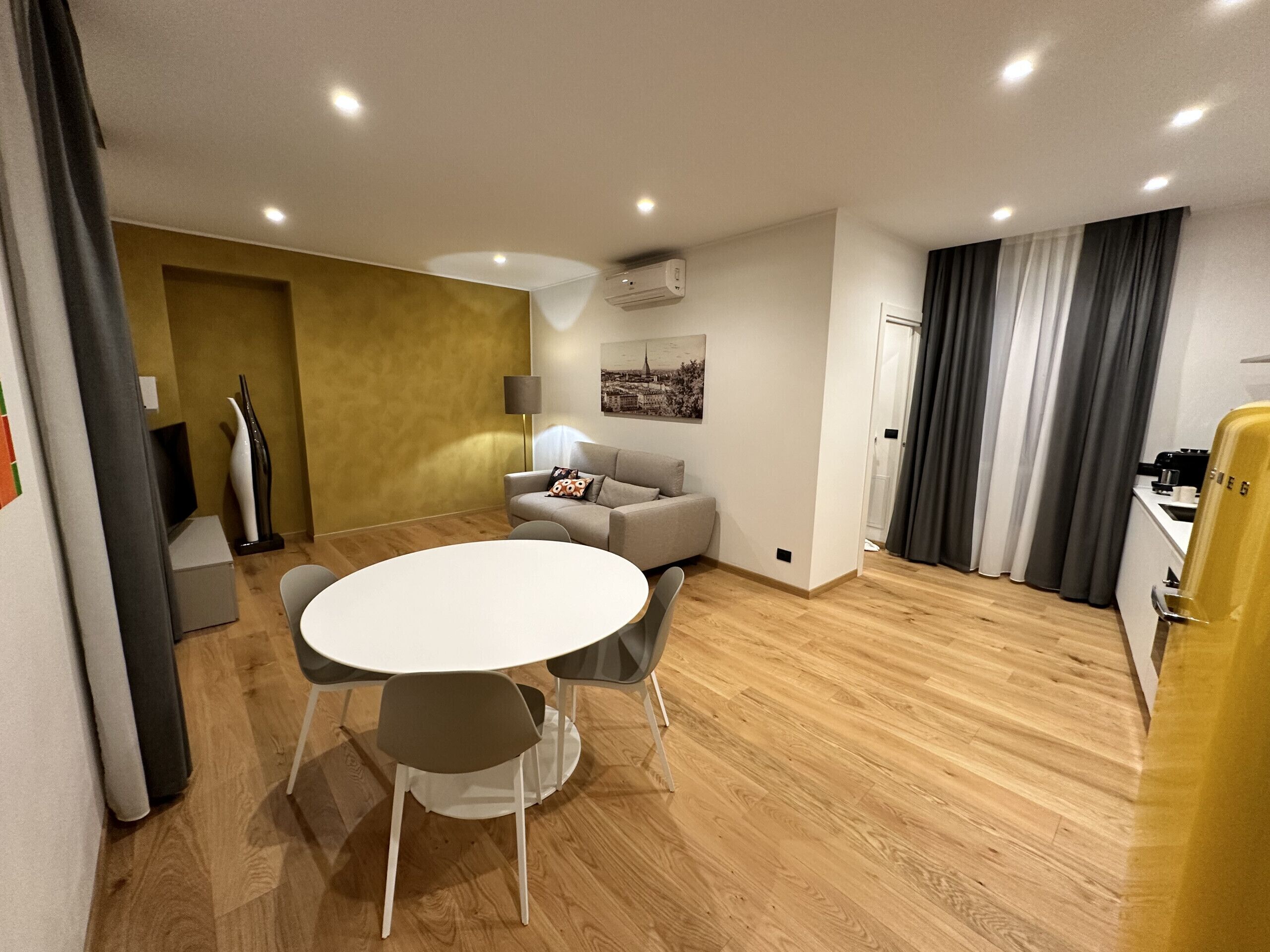 Spacious living room with kitchenette, round dining table with four chairs, sofa bed, balcony on Via Piol and SKY TV