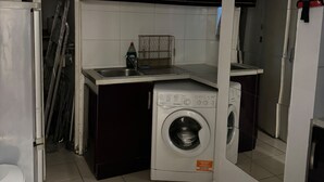 A compact kitchen with a washing machine, a refrigerator, and a sink.