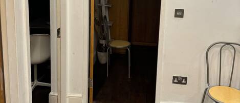A room with a wooden floor, a white door leading to a bathroom, and a chair near the door.