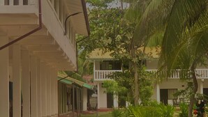 A building with a covered walkway and a palm tree. - Sea Way Hotel (Nilaveli)