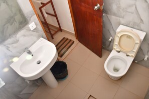 Un baño con lavamanos, inodoro y puerta de madera.