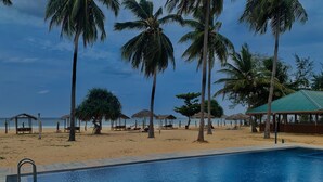 A swimming pool with a clear view of the beach and palm trees in the background. - Sea Way Hotel (Nilaveli)