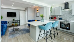 Une cuisine moderne dotée d’un îlot central, de tabourets de bar et d’un four encastré.