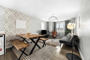 A modern living room with a dining table, bench, sofa, and floor lamp.