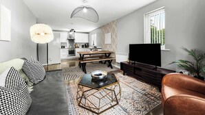 Un salon moderne comprenant un canapé, une table basse, un téléviseur et un coin repas avec une table et des chaises.