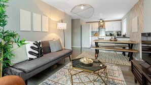 Un salon moderne comprenant un canapé, une table basse et un coin repas avec un banc et une table.